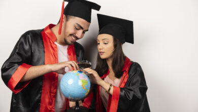 pair happy students gown looking globe white