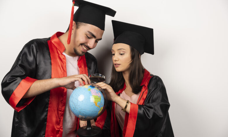 pair happy students gown looking globe white